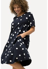 Marineblaues T-Shirt-Kleid mit weißen Punkten, kurzen Ärmeln und Taschen, im lockeren Schnitt mit einem ausgestellten Saumdesign.