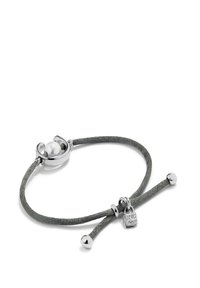 Bracelet tissé gris avec un fermoir en argent, orné d'un charme sphérique et d'une petite étiquette. Des éléments lisses et texturés rehaussent le design.