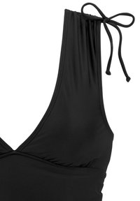 Schwarzer BikinOberteil mit tiefem V-Ausschnitt, verstellbaren Bindeträgern, gerafftem Stoff an der Brust und glatter Textur.