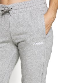 Grå bomullssweatpants med elastisk midja, justerbar dragsko, sidofickor och en liten vit logotyp på vänster lår.