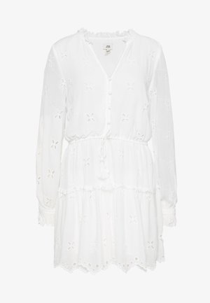 Robe mini blanche à manches longues avec broderie florale en œillet, col en V boutonné, taille à cordon et ourlet et poignets à volants.
