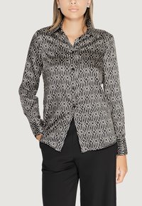 Camicia a maniche lunghe a pulsante nero e bianco con colletto, dalla texture liscia, caratterizzata da design geometrici e motivi a spirale.