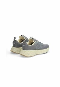 Chaussures de sport grises avec une tige texturée, une semelle intermédiaire de couleur claire dotée d'un motif moucheté, et de grandes boucles au niveau du talon.