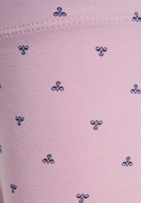 Ljusrosa tyg med en slät yta, med ett upprepat mönster av mörkblå bin. Sömmar längs kanterna.