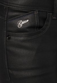 Svarta jeans i denim med Gstar-logotyp, framficka med silverdetaljer och kontrasterande blå sömmar längs sömmarna.