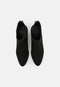 Stivaletti alla caviglia in camoscio nero con punta appuntita e tacco basso, caratterizzati da una zip decorativa lateralmente e da una fodera interna liscia.