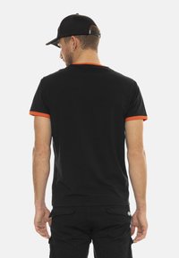 T-shirt noir avec des finitions orange sur les manches, fabriqué en coton, avec un col rond classique et des manches courtes.
