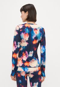 Camisola atlética de mangas longas com um padrão floral abstrato e multicolorido. Apresenta uma textura suave, design justo e buracos para os polegares nas mangas.