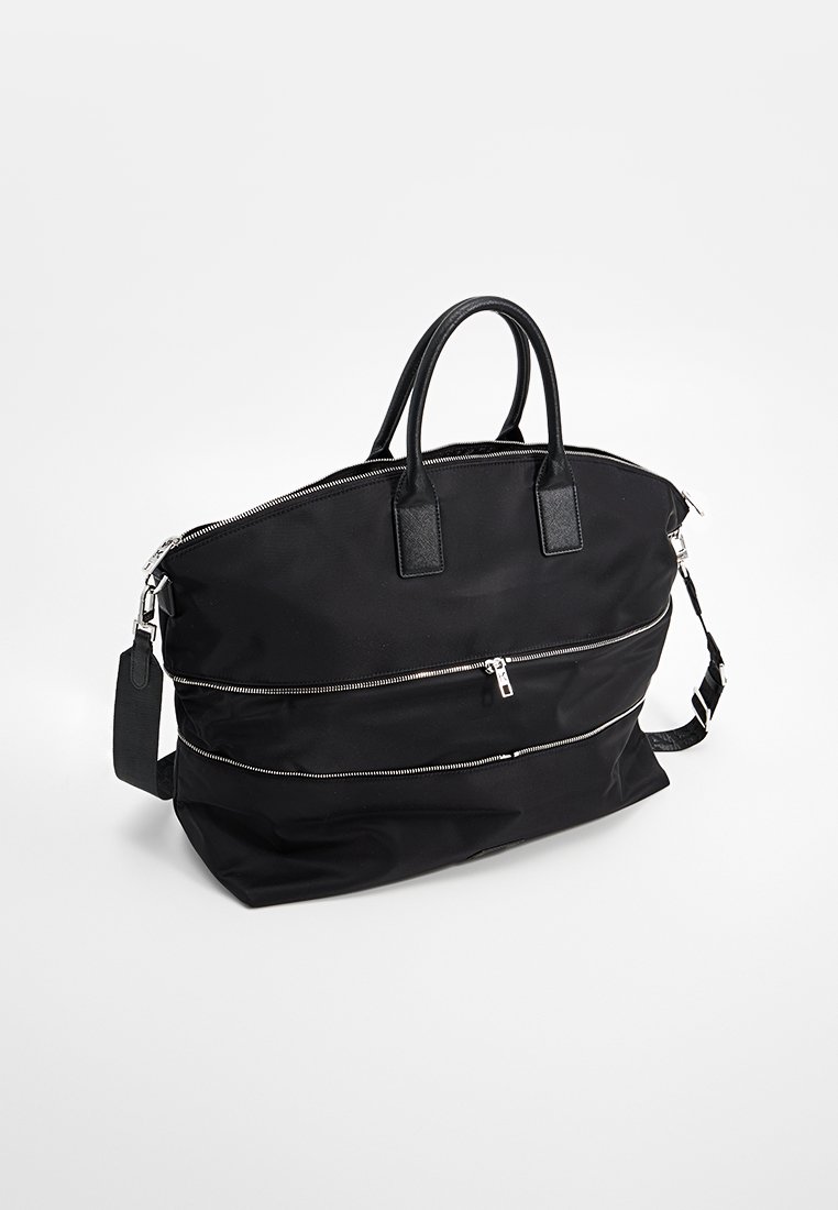 Bolso de nailon negro con asas superiores dobles y una correa para el hombro desmontable. Presenta bolsillos horizontales con cremallera y una textura suave.