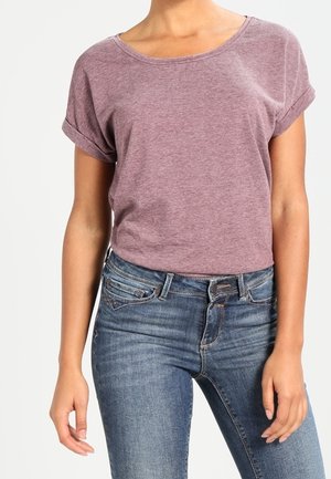 T-shirt o krótkim rękawie i okrągłym dekolcie w kolorze bordowym z podwiniętymi mankietami, zestawiony z niebieskimi dżinsami z klasycznym pięciokieszeniowym designem i lekkim spraniem.