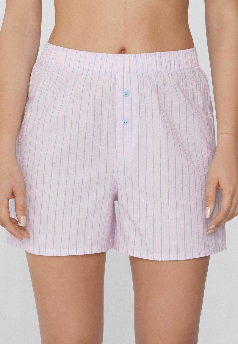 Boxers roses clairs avec des rayures bleues, taille élastique et fermeture à trois boutons à l'avant. Tissu doux avec une texture légère.