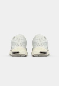 Para białych i szarych butów do biegania Nike pokazana z tyłu, z siateczkową cholewką i podeszwią z amortyzacją powietrzną.