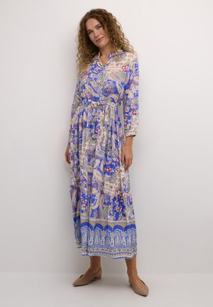 Langsam blauer Kleid mit einem Paisleymuster und floralen Akzenten, mit Kragen und tailliertem Bund. Der Stoff wirkt leicht und fließend.