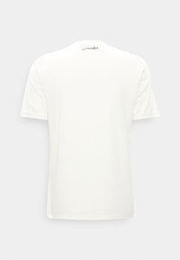 T-shirt blanc à manches courtes vu de dos avec un détail en écriture arabe noire près de l'encolure sur un fond uni.