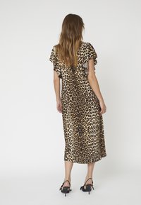 Rochie midi cu imprimeu de leopard dintr-un material ușor, cu mâneci fluturate. Are o croială lejeră și un tiv rotunjit. Asortată cu sandale cu toc negre.