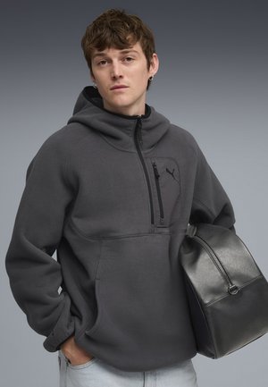 Dunkelgrauer Fleece-Pullover mit einer Reißverschlusstasche auf der Brust und Kapuze. Verfügt über ein dezentes Logo auf der Tasche und eine Front-Kängurutasche.