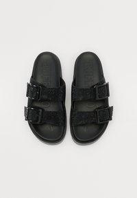 Sorte sandaler med to justerbare remmer som har en teksturert, glitrende finish og en solid, matt svart såle. "BUFF" er preget på innersålen.