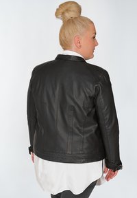 Schwarze Lederjacke mit tailliertem Schnitt, ausgestattet mit einem flachen Kragen, dezenten Nähten und verstellbarem Material an den Bündchen.