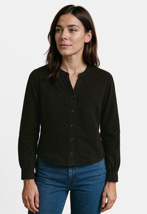 Zwarte overhemden met lange mouwen, gestructureerde stof, ronde halslijn en ruitpatroon aan de voorkant. In combinatie met blauwe jeans.