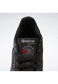 Čierne tenisky Reebok s textilným zvrškom, logo v zlate, s geometrickým dizajnom a červenými a bielymi akcentmi na jazyku.