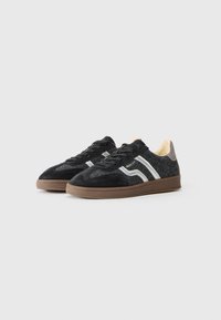 Sneaker in suede nero e tessuto testurizzato con strisce bianche e suole in gomma marrone. Caratterizzate da lacci e linguetta con un accento chiaro.