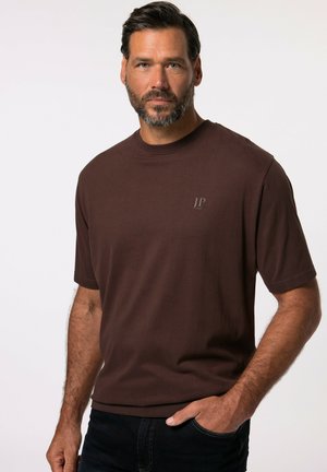 Camiseta corta marrón de manga corta, hecha de algodón, con un escote redondo y pequeño logo JP en el pecho. Textura suave, diseño ajustado.