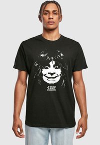 Juodas medvilninis marškinėliai su baltu atspaudu, vaizduojančiu veidą su ilgais plaukais, o apačioje yra stilizuota užrašas "Ozzy Osbourne".