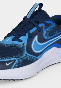 Μπλε και ναυτικό αθλητικό παπούτσι Nike με μαύρα κορδόνια, επάνω μέρος από διαπνέον δίχτυ, λευκό λογότυπο Nike swoosh και λευκή επενδεδυμένη σόλα.