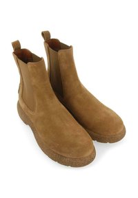 Bottines Chelsea en daim marron avec des panneaux latéraux élastiques et des semelles en caoutchouc texturé. Équipées de languettes pour un enfilage facile.