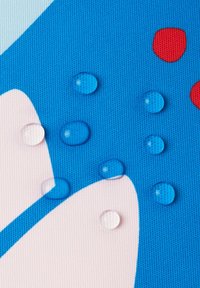 Texturierte blaue Oberfläche mit mehrfarbigen Mustern. Klare Wassertropfen sind sichtbar, reflektieren Licht und variieren in der Größe. Rote und rosafarbene Akzente sind vorhanden.