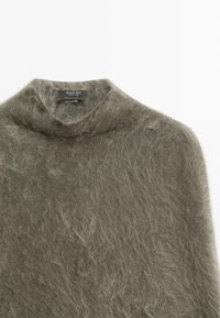Maglione in cashmere verde oliva con collo alto, texture morbida e finitura pelucchosa. Etichetta con la dicitura "Massimo Dutti, 100% cashmere."