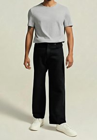 Camiseta gris de manga corta combinada con pantalones negros de tiro alto, que presentan un corte relajado y zapatillas blancas clásicas.