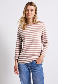 Gestreepte lange mouw top in lichtroze en crème kleuren, gemaakt van katoen, met een ronde halslijn en een losse pasvorm, gecombineerd met blauwe jeans.
