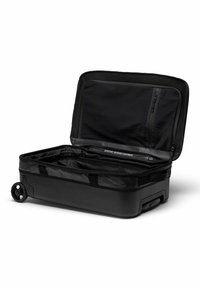 Valise à roulettes noire avec une coque rigide, des compartiments intérieurs zippés et des roulettes lisses. Ouverte, montrant l'espace de rangement disponible.