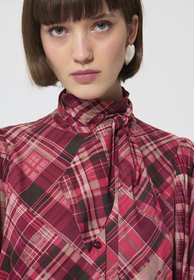 Rood en beige geruite blouse met een hoge kraag en nekband. Voorzien van een knoopsluiting, lange mouwen en een vloeiende, gestructureerde stof.