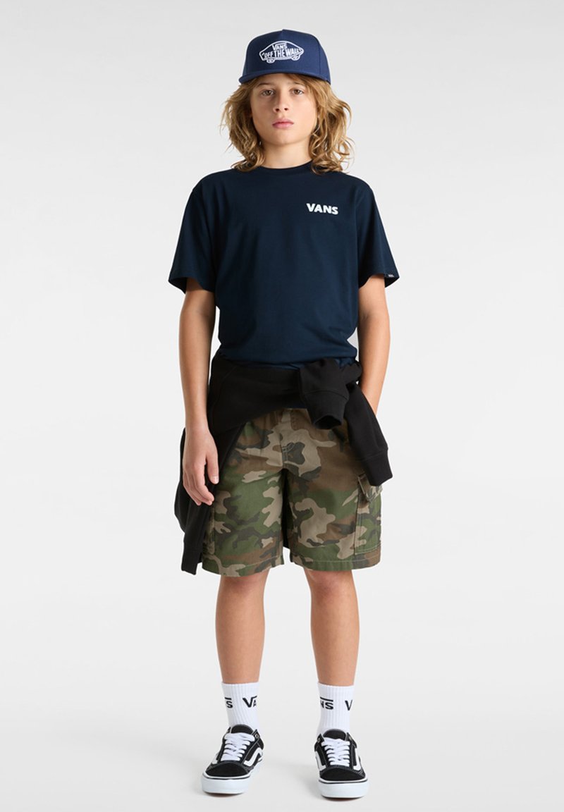 Námořnické tričko s logem "VANS", maskáčové kraťasy, černá mikina uvázaná v pase, černé tenisky, bílé ponožky s logem "VANS". Modrá kšiltovka.