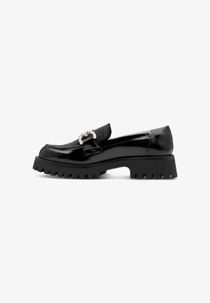 Schwarze Lacklederschuhe mit einem gesteppte schwarzen Lederband, silbernem Beschläge, dicker gezahnter Sohle und niedrigem Absatz.