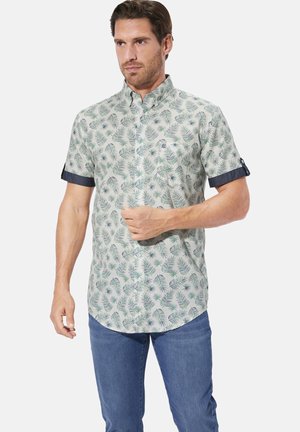 Light green short-sleeve shirt with palm leaf pattern, button-down collar, and denim accents on the cuff. Worn with blue jeans.