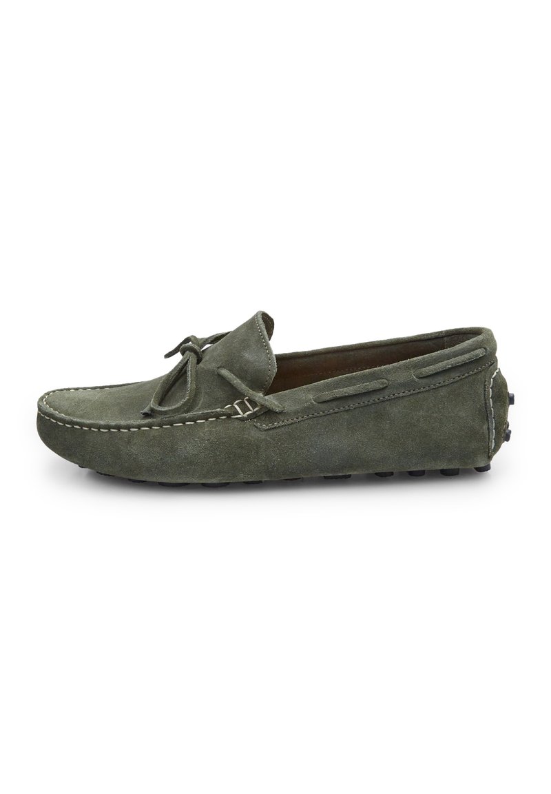 Olivgrüne Wildleder-Mokassinschuhe mit runder Zehenpartie, dekorativem Bogen und kontrastierender weißer Nähte. Flache Gummisohle mit rutschfester Struktur.