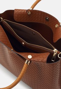 Bruine geweven leren handtas met een gevlochten handvat, gouden beslag en een ritssluiting met een bruine stoffen voering.