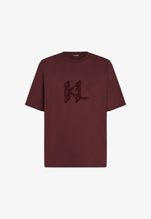 Burgundi värvi puuvillane T-särk lühikeste varrukatega, mille esipinnal on tekstuuriga "KL" logo, mis on valmistatud sädelustest. Klassikaline ümmargune kaelus.