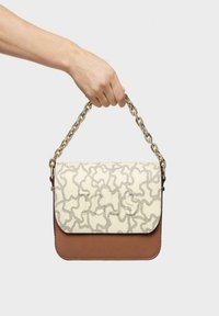 Bolso de mano marrón y crema con un patrón texturizado, cadena dorada y fondo de cuero liso. Cierre de broche en la parte superior.