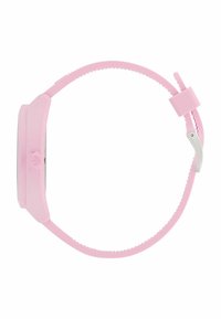 Montre en silicone rose avec un cadran rond et un bracelet texturé. Présente un fermoir en argent et un détail de logo bien visible sur le côté.