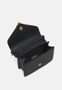 Bolso de mano de cuero negro con cierre de botón magnético, herrajes en tono dorado, bolsillo interior con cremallera y un diseño elegante y minimalista.