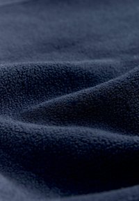 Tissu en polaire bleu marine avec une surface douce et texturée présentant des plis et des ondulations délicates, mettant en valeur son épaisseur et sa chaleur.