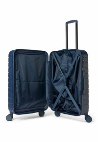 Valise rigide bleu marine avec fermeture à glissière, sangles intérieures et roulettes silencieuses. Le tissu intérieur est foncé et lisse.