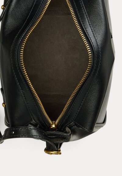 Sac à main en cuir noir ouvert montrant l'intérieur en tissu marron avec une fermeture éclair dorée et une bandoulière en cuir noir avec une boucle dorée.