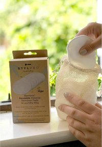 Bamboo reusable makeup remover pads in a mesh laundry bag, with a cardboard box featuring a circular design. Color: white and brown.