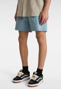 Blå bomulds shorts, letvægts stof, over-kn�æ længde. Kombineret med sorte og hvide Vans sneakers og en beige stribet skjorte.