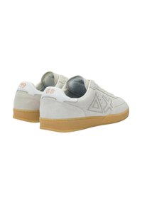 Scarpe da ginnastica in suede bianco con suole in gomma, caratterizzate da una superficie testurizzata, un design geometrico sui lati e numeri a contrasto sul tallone.
